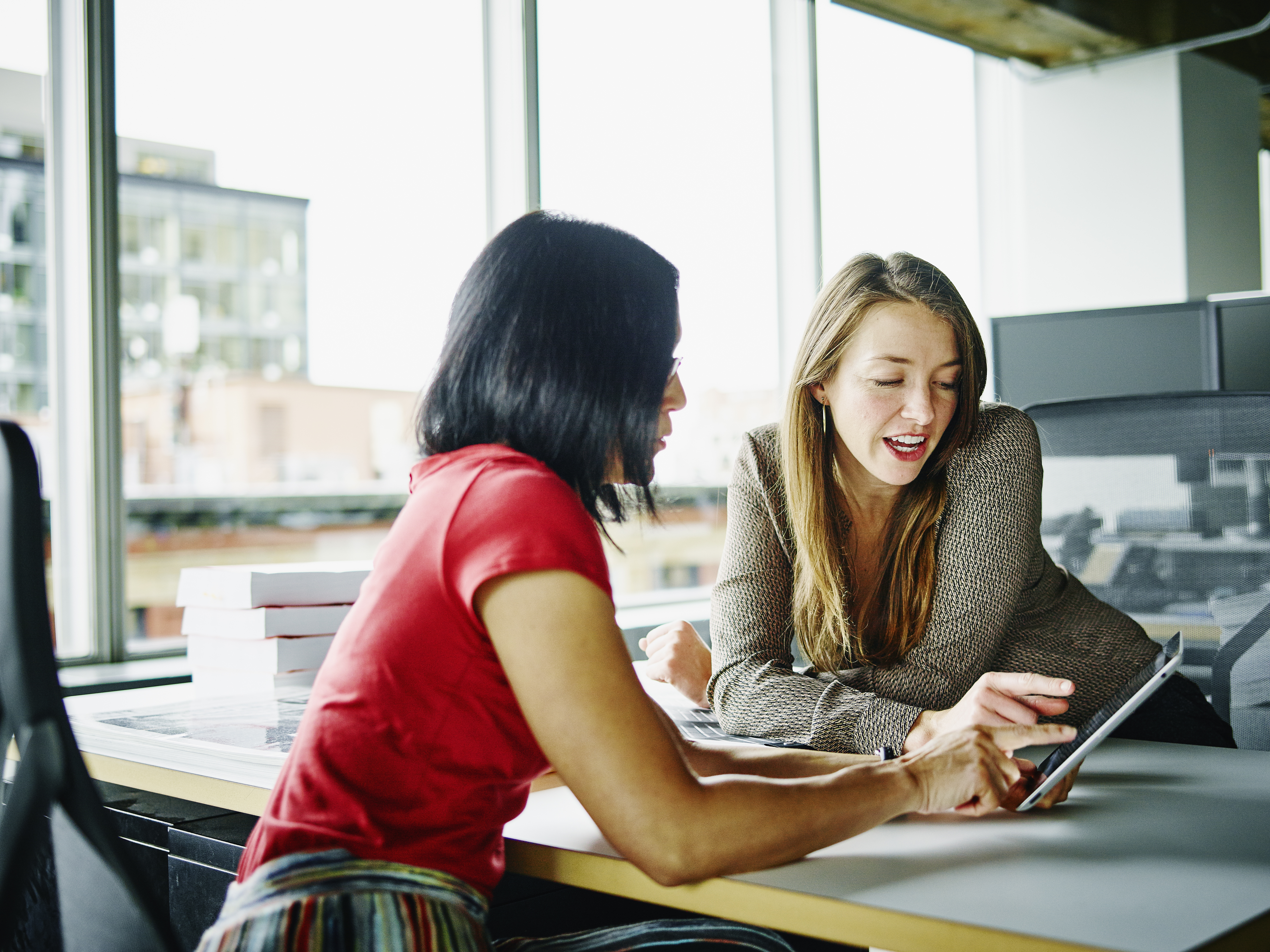 two women talking while looking at tablet